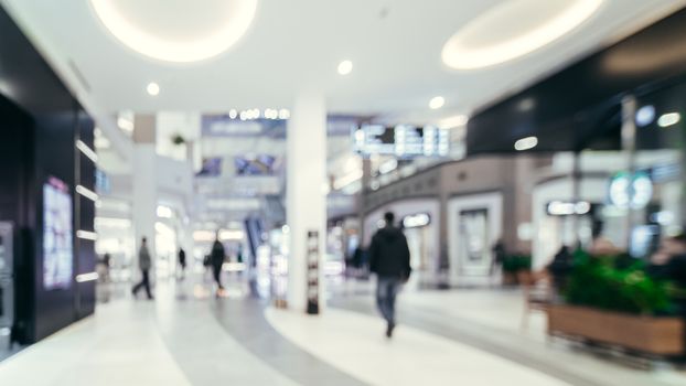 Shopping mall blur background with bokeh. Blurred hall of shopping mall with customers as background. Copy space