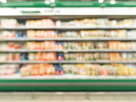 Defocused blur of supermarket shelves with dairy and mayonnaise products in refrigerator. Blur background with bokeh. Defocused image