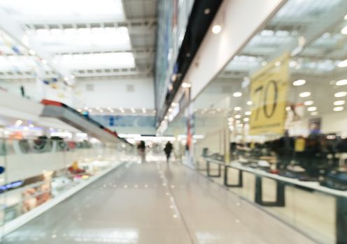 Shopping mall blur background with bokeh. Blurred hall of shopping mall with customers as background. Copy space