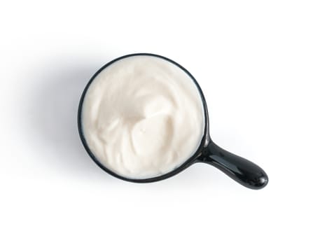 Beautiful greek yogurt or sour cream in black bowl, isolated on white background with clipping path. Top view or flat-lay.