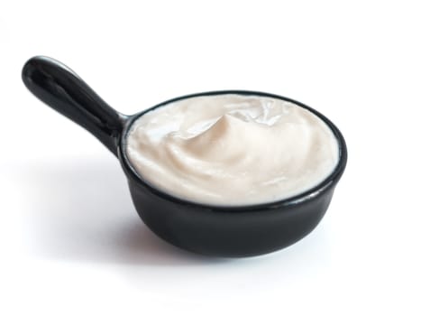 Beautiful greek yogurt or sour cream in black bowl, isolated on white background with clipping path. Copy space for text