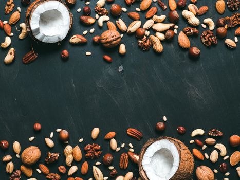 Background of mixed nuts - coconut, hazelnuts, walnuts, almonds, pecan, pistachio, brazil nut, pine nuts, peanut - on dark background. Copy space. Top view or flat lay