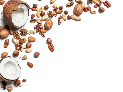 Background of mixed nuts - coconut, hazelnuts, walnuts, almonds, pecan, pistachio, brazil nut, pine nuts, peanut - with copy space. Isolated one edge. Top view or flat lay