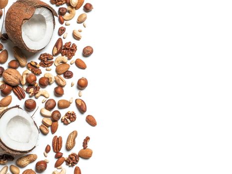 Background of mixed nuts - coconut, hazelnuts, walnuts, almonds, pecan, pistachio, brazil nut, pine nuts, peanut - with copy space. Isolated one edge. Top view or flat lay