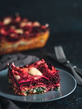 Vegetable Packed Rainbow lasagne on dark background.Ideas and recipes for healthy vegetarian dinner or lunch.Lasagne with beetroot, pumpkin, mushrooms, ricotta, spinach, mozarella. Copy space for text