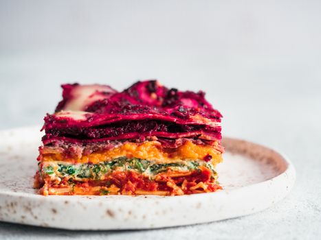 Vegetable Packed Rainbow Lasagne on craft plate. Ideas and recipes for healthy vegetarian dinner or lunch. Lasagne with beetroot, pumpkin, mushrooms, ricotta, spinach, mozarella. Copy space for text.