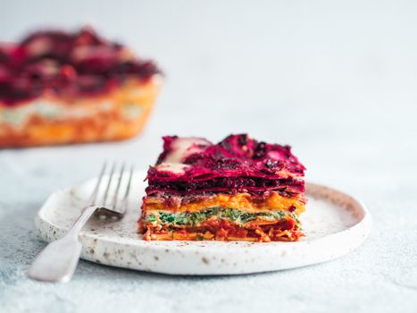 Vegetable Packed Rainbow Lasagne on craft plate.Ideas and recipes for healthy vegetarian dinner or lunch. Lasagne with beetroot,pumpkin,mushrooms,ricotta,spinach,mozarella on white table. Copy space