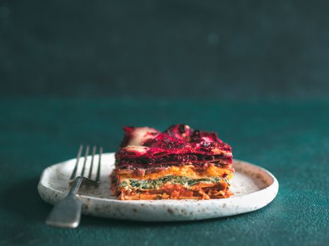 Vegetable Packed Rainbow lasagne on green background.Ideas and recipes for healthy vegetarian dinner or lunch.Lasagne with beetroot, pumpkin, mushrooms, ricotta, spinach, mozarella.Copy space for text
