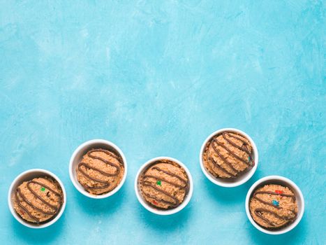 Safe-to-eat raw monster cookie dough in small portion bowl on blue background. Ideas and recipes for kids and toddlers meal. Top view or flat-lay. Copy space for text.