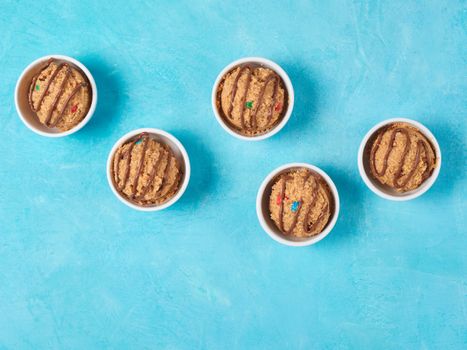 Safe-to-eat raw monster cookie dough in small portion bowl on blue background. Ideas and recipes for kids and toddlers meal. Top view or flat-lay. Copy space for text.