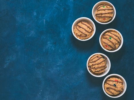 Safe-to-eat raw monster cookie dough in small portion bowl on blue background. Ideas and recipes for kids and toddlers meal. Top view or flat-lay. Copy space for text.