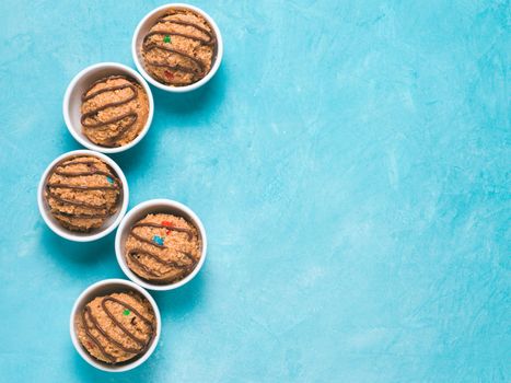 Safe-to-eat raw monster cookie dough in small portion bowl on blue background. Ideas and recipes for kids and toddlers meal. Top view or flat-lay. Copy space for text.