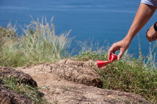 Man picking up litter can on rock at seaside