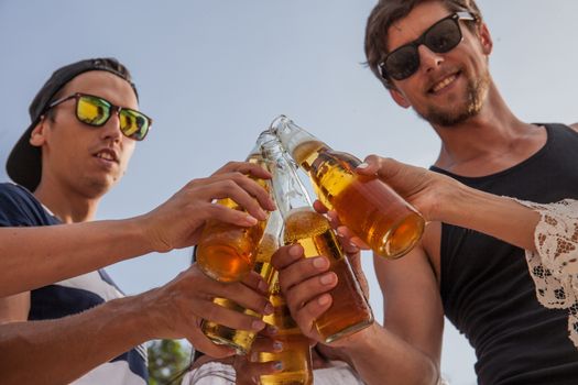 Happy young friends drinking beer outdoors