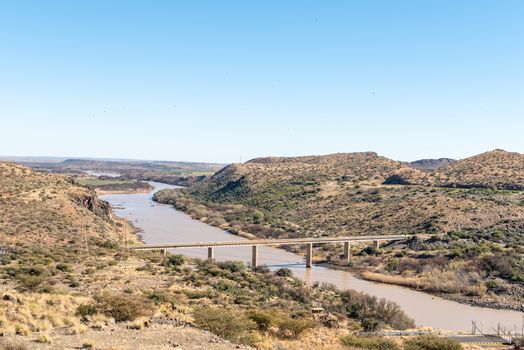 View downstream from the wall of the Vanderkloof Dam in the Orange River. The The river and single lane road bridge are visible