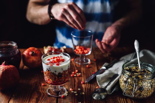 Dessert with Pomegranate and Man Prepare New Portion on Backdrop. Series on Prepare Healthy Dessert with Pomegranate, Granola, Cream and Jam
