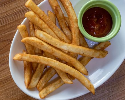 French fries and ketchup on plate, shot from above