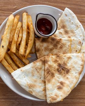 Quesadilla and french fries on plate, shot from above