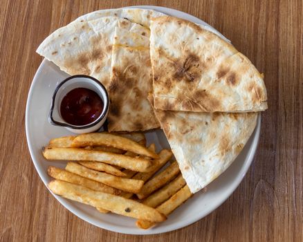 Quesadilla and french fries on plate, shot from above