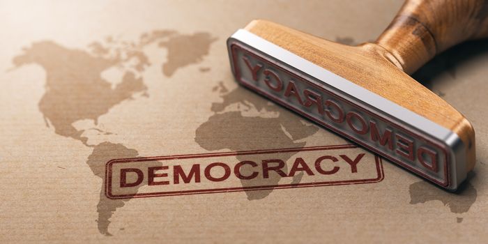 Rubber stamp over paper background with a world map watermark printed and the word democracy. Concept of political militancy around the world. 3D illustration.