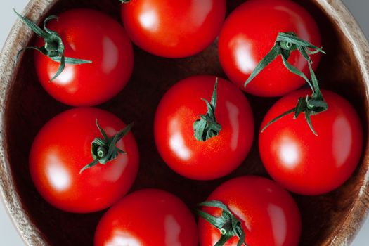 Fresh red cherry tomatoes in wooden bowl. Close-up, top view. Macro, flat lay. Horizontal.