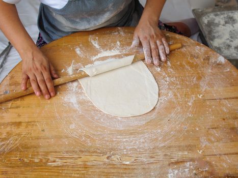 woman who makes "bazlama" and "yufka". raw dough opens with rolling pin