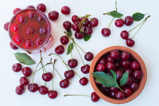 cherry on the wooden table, sour cherry and a glass of cold cherry juice. top view