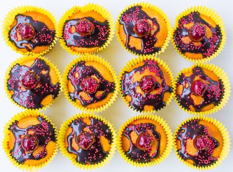 Delicious homemade cupcakes isolated on a white background with cherry, confectionery and chocolate sauce. Top view.