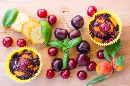 Delicious homemade cupcakes isolated on a wooden background with cherry, confectionery and chocolate sauce. served with fruit pieces. Top view.