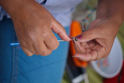 a woman stitch a child's clothe. hand work, lace weave.