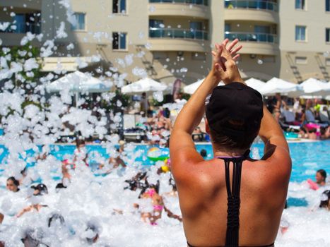 nice brunette woman at the foam party in the hotel pool. summer vacation