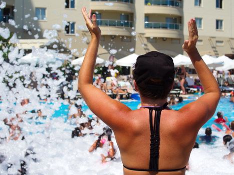 nice brunette woman at the foam party in the hotel pool. summer vacation