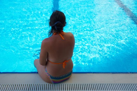 Beautiful auburn woman in hotel pool. The enjoyment of summer vacation
