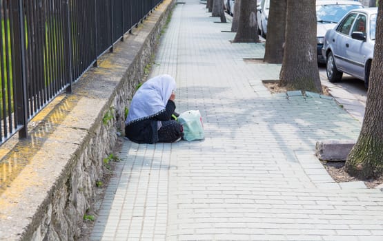 beggar sitting on the street. female beggar. Wants money for Ramadan