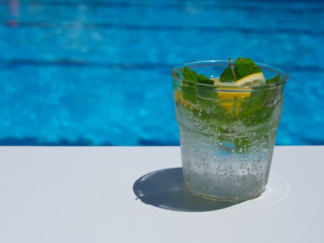 enjoying fresh lemon and mint mojito cocktail by the pool