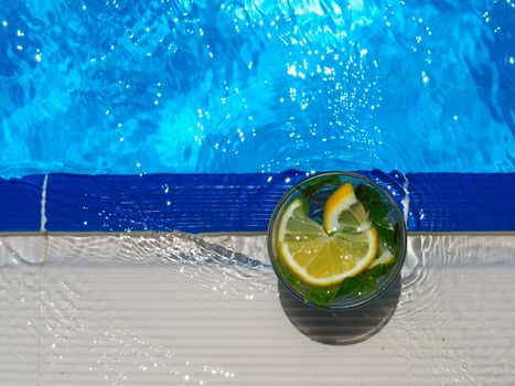 enjoying fresh lemon and mint mojito cocktail by the pool