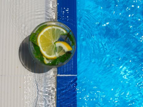 enjoying fresh lemon and mint mojito cocktail by the pool