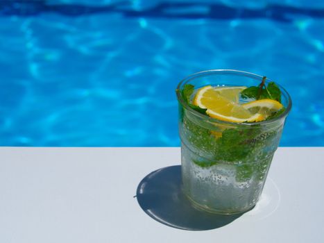 enjoying fresh lemon and mint mojito cocktail by the pool