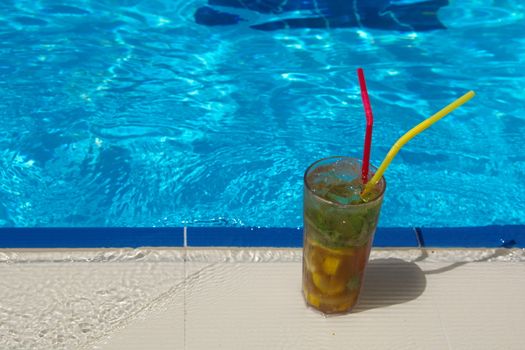 enjoying fresh lemon and mint mojito cocktail by the pool