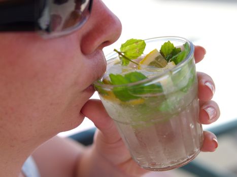 the woman smokes mojito cocktail. enjoying fresh lemon and mint mojito cocktail by the pool