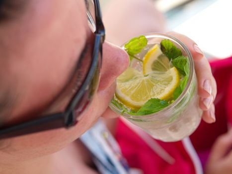 the woman smokes mojito cocktail. enjoying fresh lemon and mint mojito cocktail by the pool