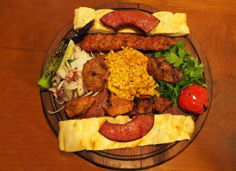 mixed turkish kebab. famous turkish food. served on the board with cooked tomatoes, peppers, onions and fresh greens