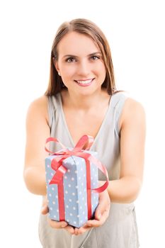 Beautiful young woman holding a wrapped gift, making an impression she's giving it to you, isolated on white background.