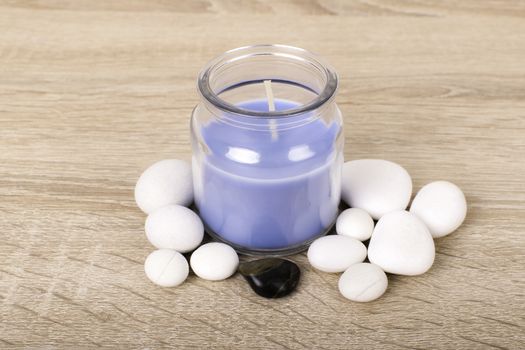 Zen white and black stones and aromatic blue candle on a wooden background.