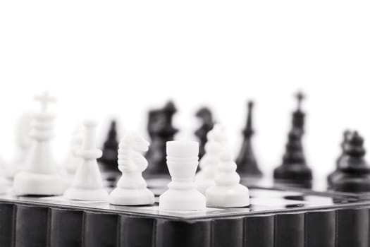 A close up shot of a black and white chess table, with white figures in focus and black figures blurred, isolated on white background.