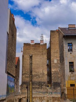 Empty construction site between old brick buildings against a blue sky. Construction of a building among the ruined neighboring buildings in Budapest. 