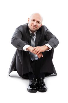 Business success concept - handsome happy smiling businessman in black suit sitting down floor white isolated