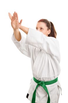 Block this way. Young girl wearing kimono with green belt in block stance, isolated on white background.