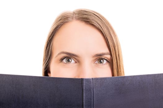 Close-up shot of a young girl making hiding behind her book, isolated on white background.