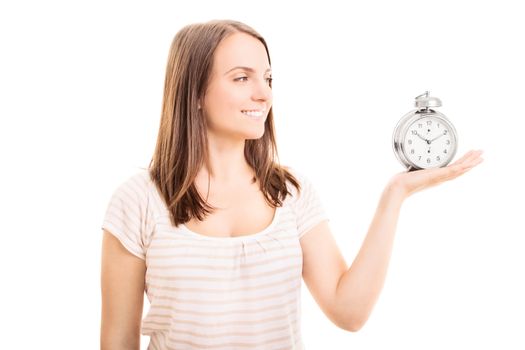 Beautiful young girl holding an old-fashioned alarm clock leaving an impression that it's time for something, isolated on white background.